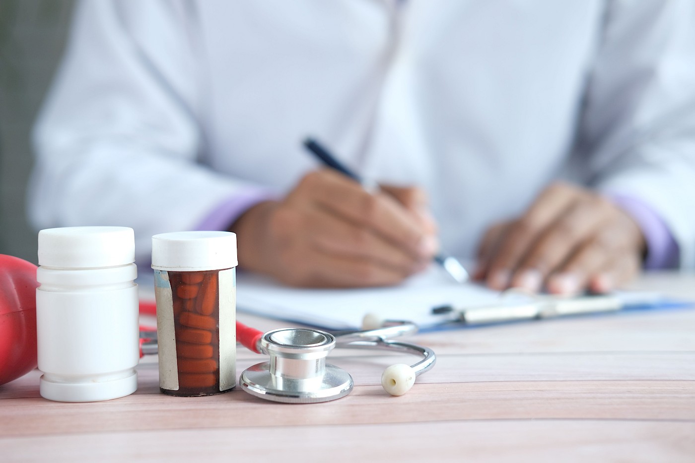 close up of medicine bottle and tablets in front of hands writing
